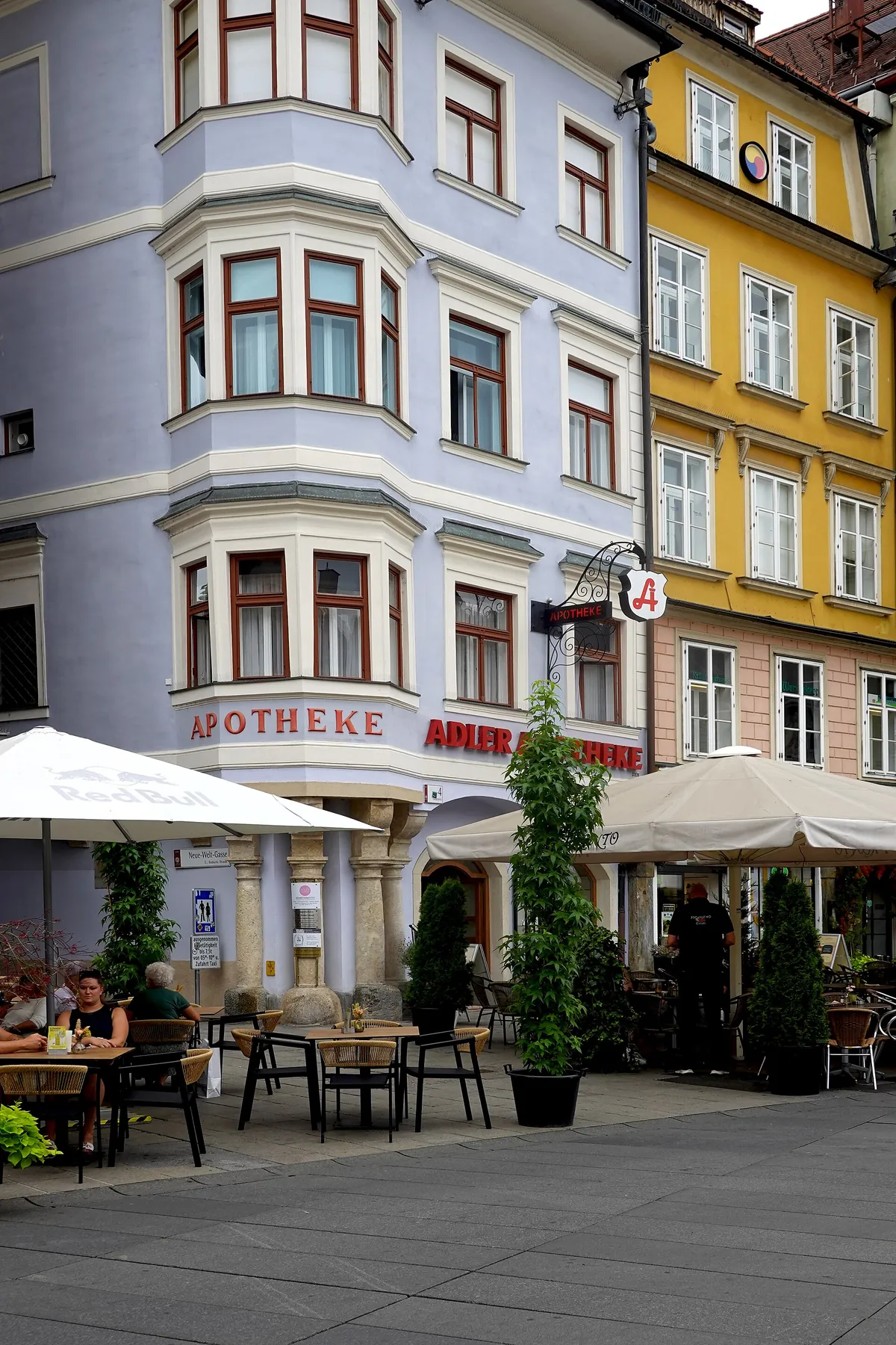 Eckhaus mit Erkern am Grazer Hauptplatz, im Erdgeschoss die Adler Apotheke mit Schanigärten davor