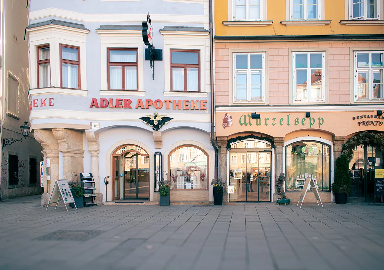 Außenansicht der Adler Apotheke und des Wurzelsepp am Hauptplatz
