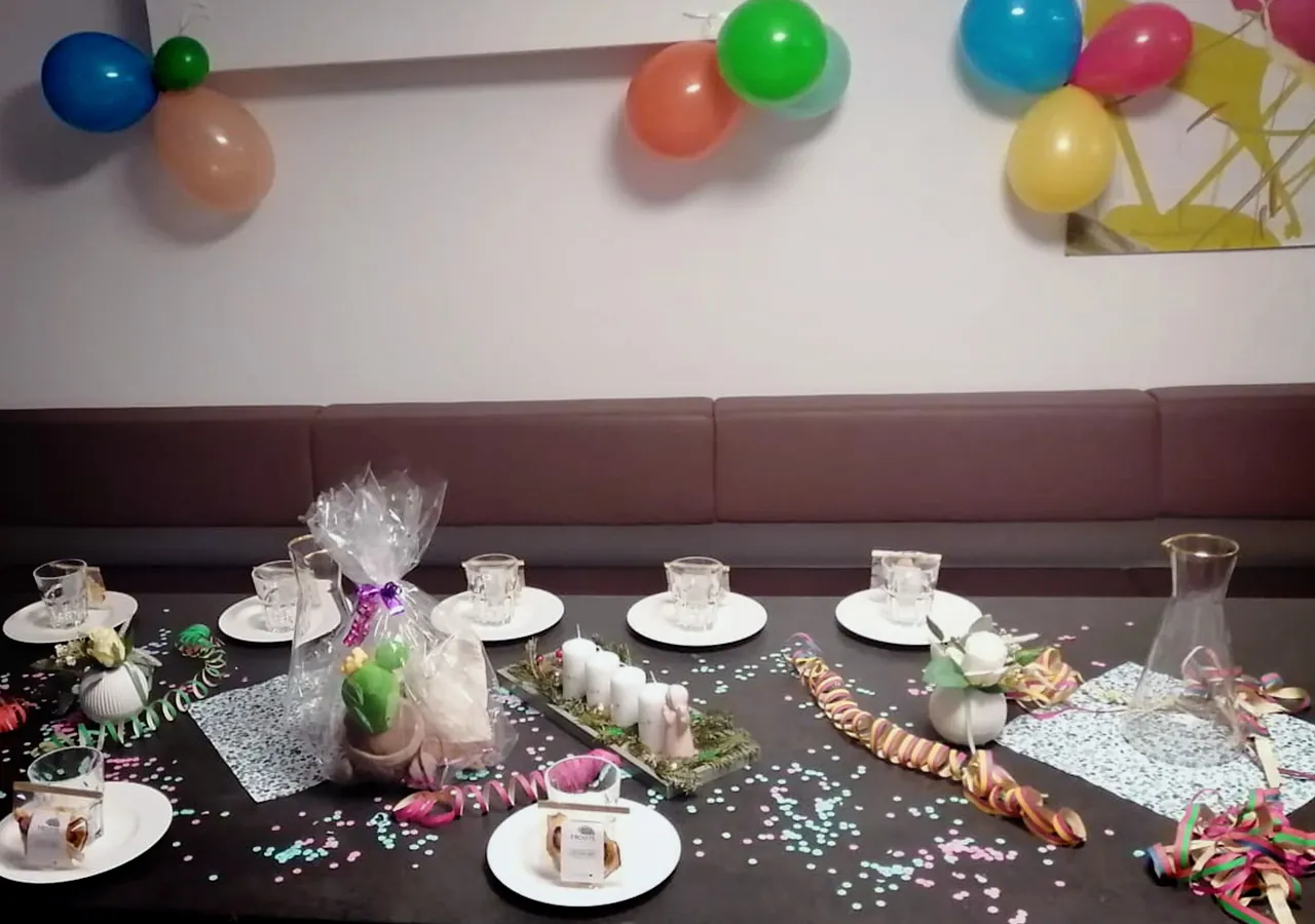 Festlich dekorierter Tisch mit Gedecken, Konfetti, Luftschlangen und Geschenkpaketen