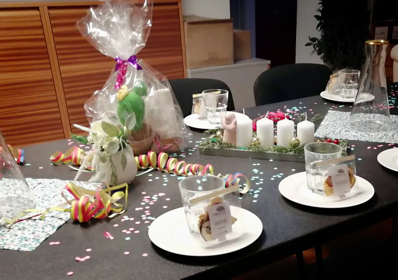 Tisch mit einzeln verpackten Gebäckstücken, Gläsern, Karaffen und einem verpackten Geschenk