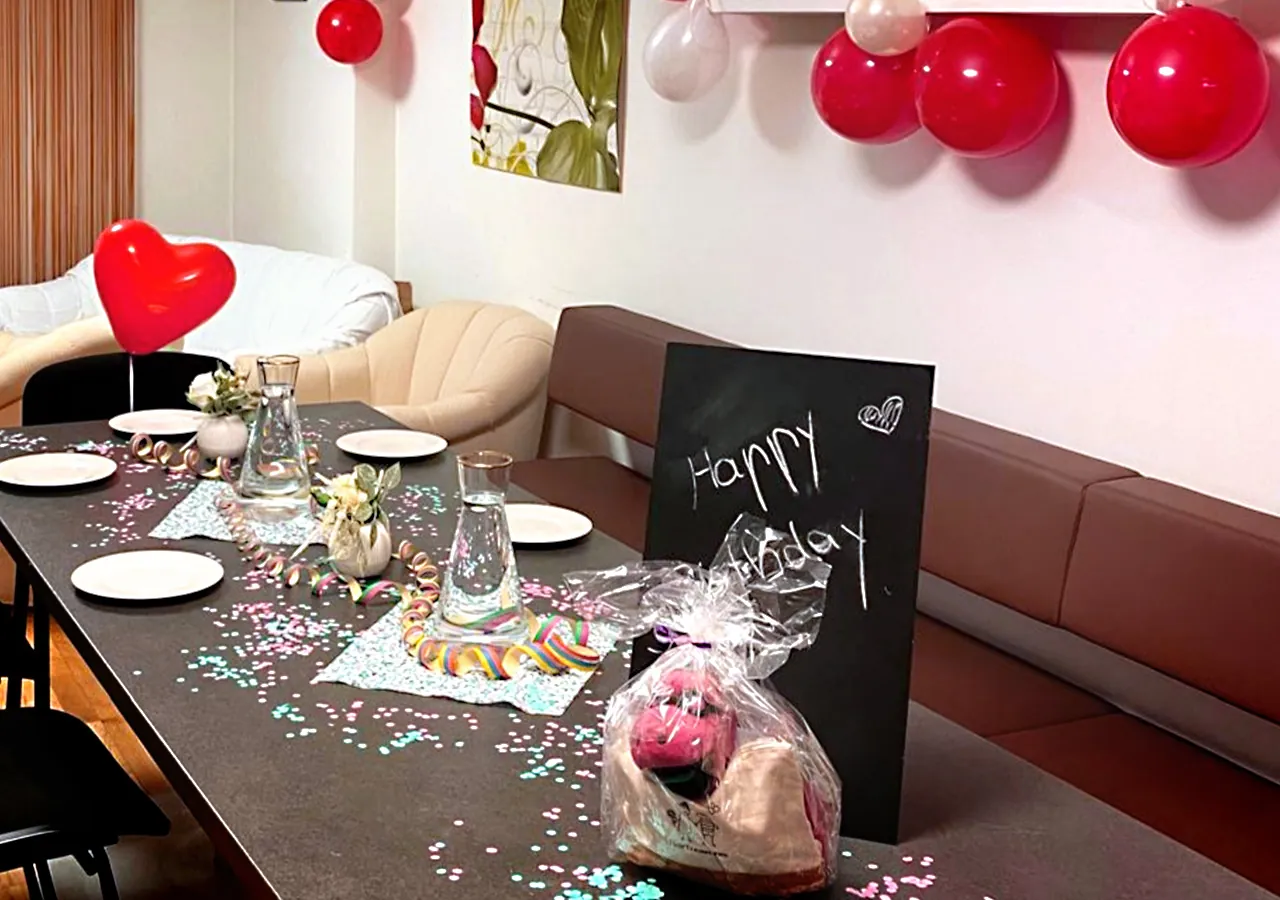 Festlich gedeckter Tisch in der Adler Apotheke mit Konfetti, Luftballons und einer Tafel „Happy Birthday“