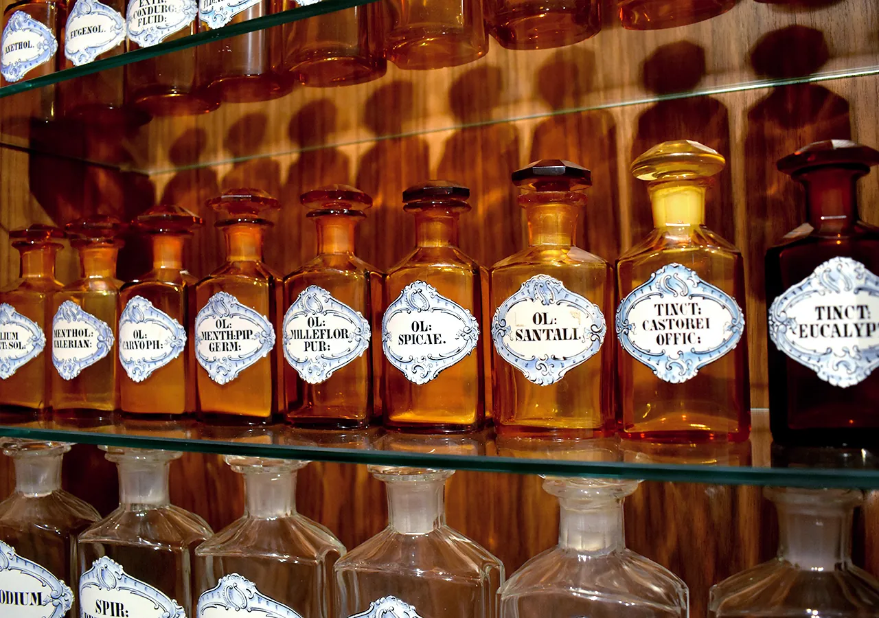 Reihe historischer Apothekerflaschen mit Etiketten wie „Öl Spicae“ und „Tinktur Eucalyptus“