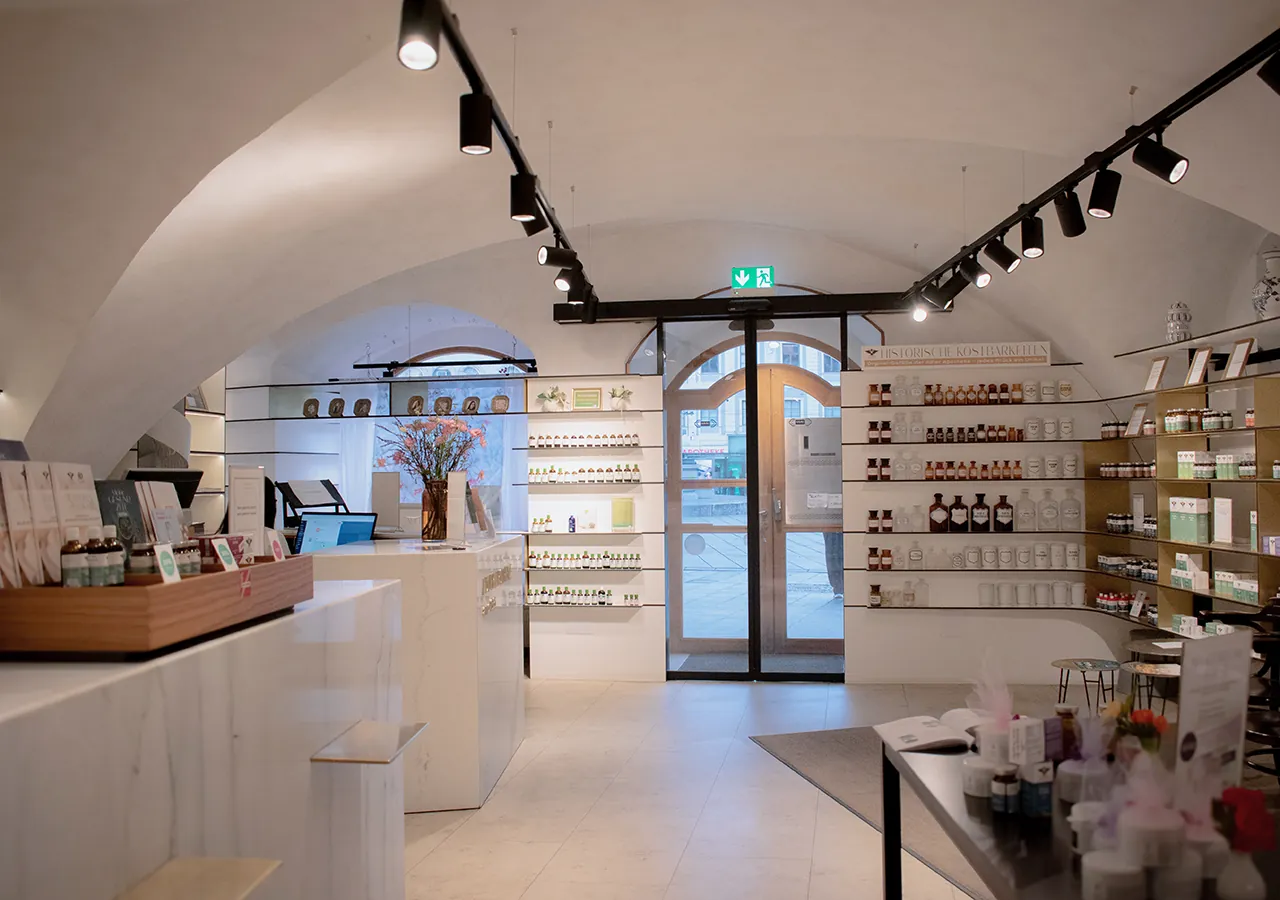 Modernes Ambiente in der Adler Apotheke mit Marmortresen, Regalen und großer Glastür