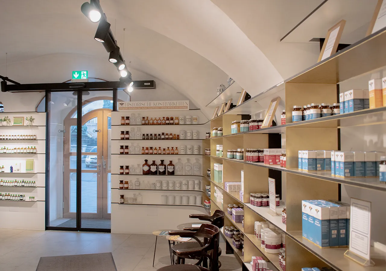 Helle Regale mit Pflegeprodukten und Arzneimitteln beim Eingang der Adler Apotheke