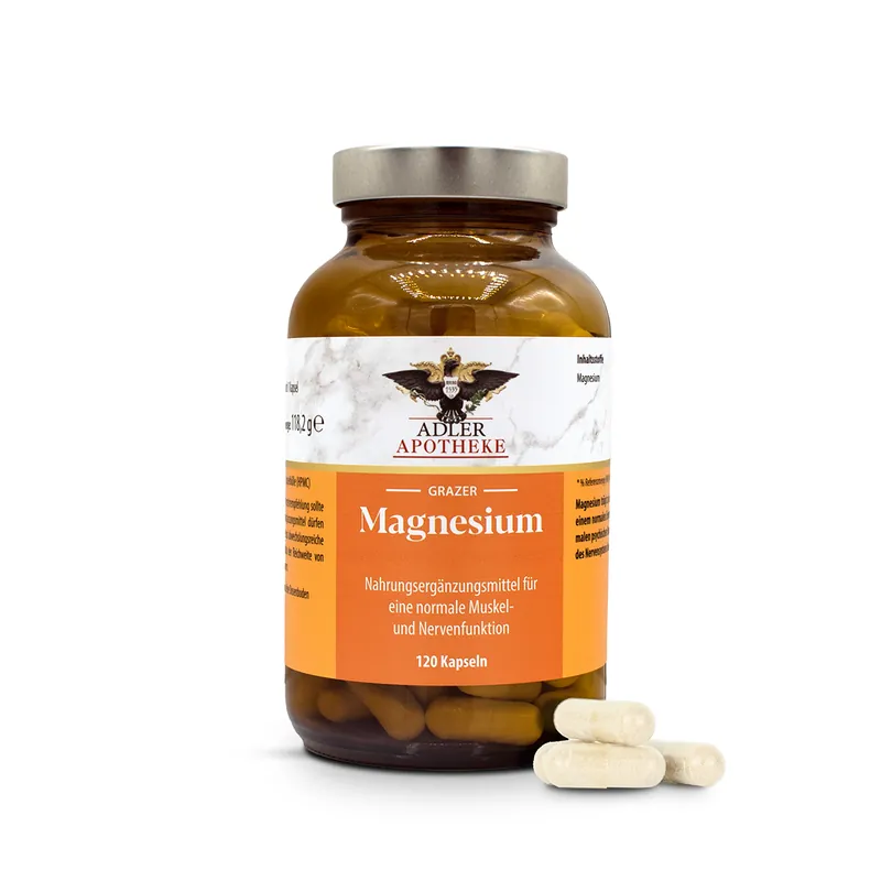 Ein dunkelbraunes Glas mit silbernem Schraubverschluss und orangen Etikett der Grazer Magnesium Kapseln. Im Vordergrund liegen 4 weißen Kapseln zur Ansicht.