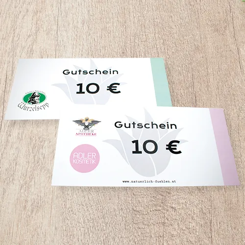 Geschenkgutscheine der Adler Apotheke und Adler Kosmetik auf einem Holztisch