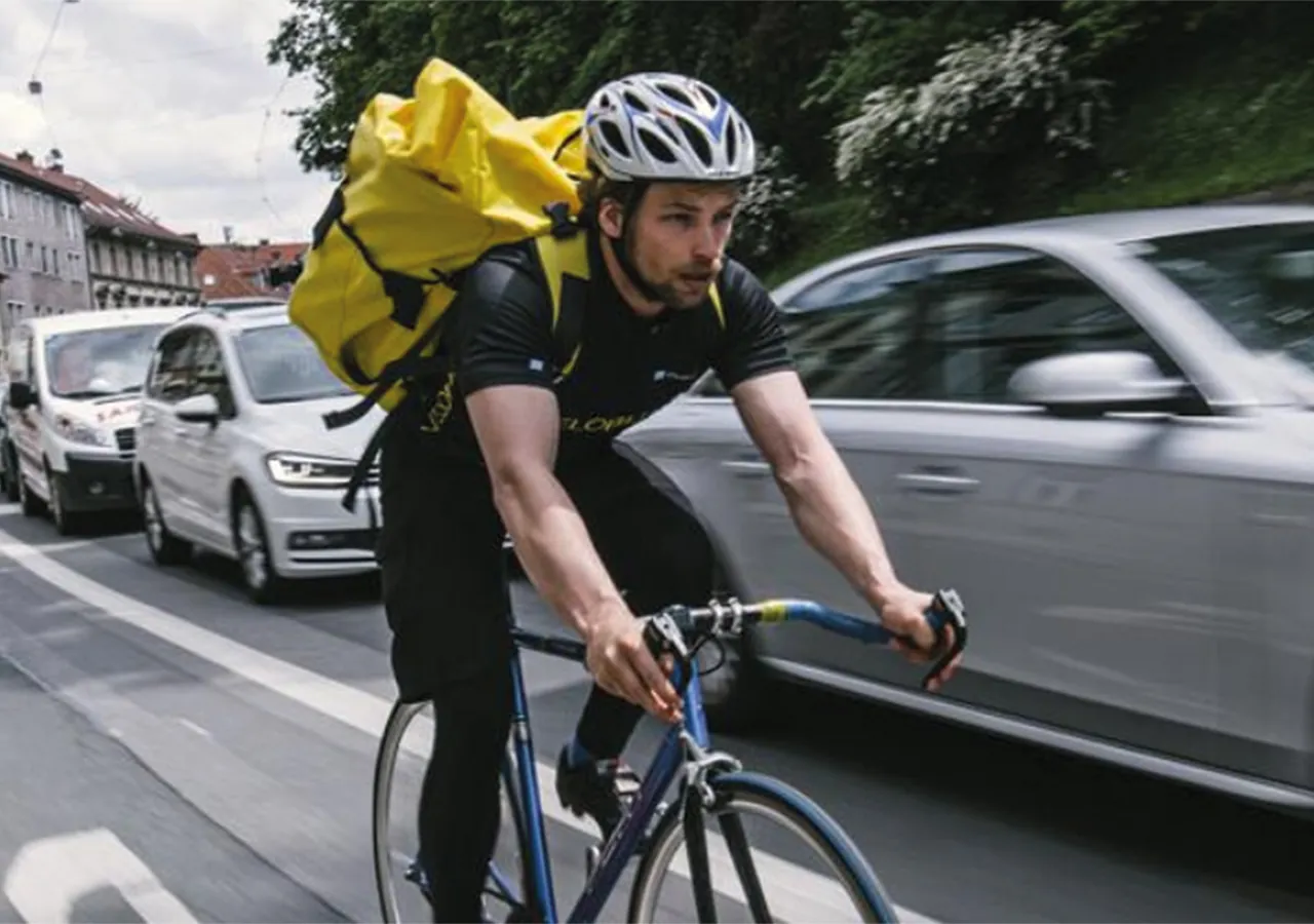 Radbote mit gelbem Rucksack fährt durch die Grazer Innenstadt